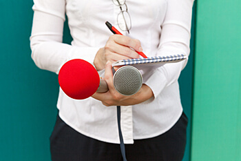 Berufsinterviews Frau hält Mikrofon und macht Notizen