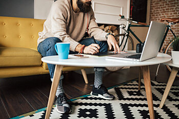 junger Mann sitzt am Laptop und macht Notizen
