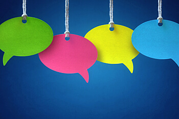 Erfahrungsberichte an Schnüren aufgehängte farbige Post-its in Form einer Sprechblase