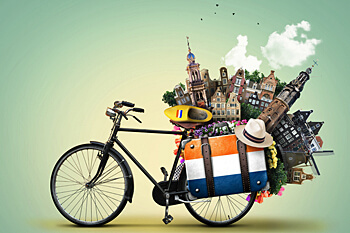 Ein Fahrrad mit Koffer auf dem Gepäckträger, der Koffer hat die Farben der niederländischen Flagge und typisch niederländische Gegenstände ragen aus dem Koffer hervor