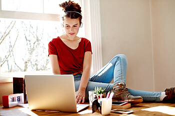 Studiengaenge Psychologie Studentin schreibt Text an Laptop und hört Musik