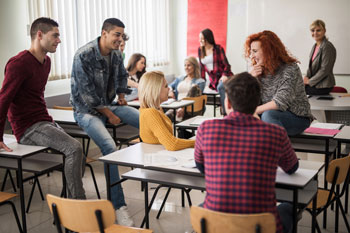 Psychologie Studenten sitzen in Seminarraum und unterhalten sich vor Kursbeginn