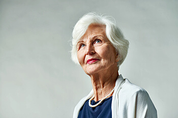 ältere Frau mit Blick nach oben vor weißem Hintergrund