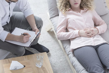 Psychologe in Gesprächstherapie mit junger Frau auf Sofa